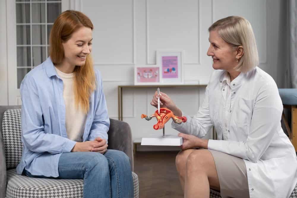 Mjeke gjinekologjike shpjegon operacionin për prolapsin e mitrës me model të organeve pelvike.